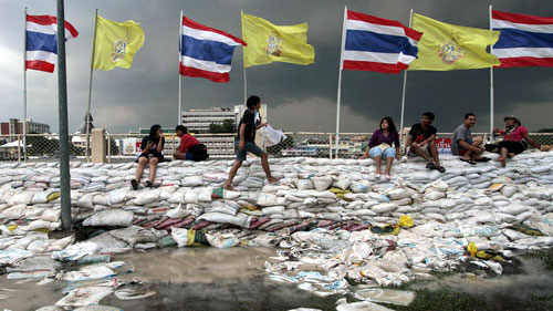 Các tình nguyện viên ngồi trên các bao cát ngăn lũ (Ảnh: Bangkok Post)
 
.